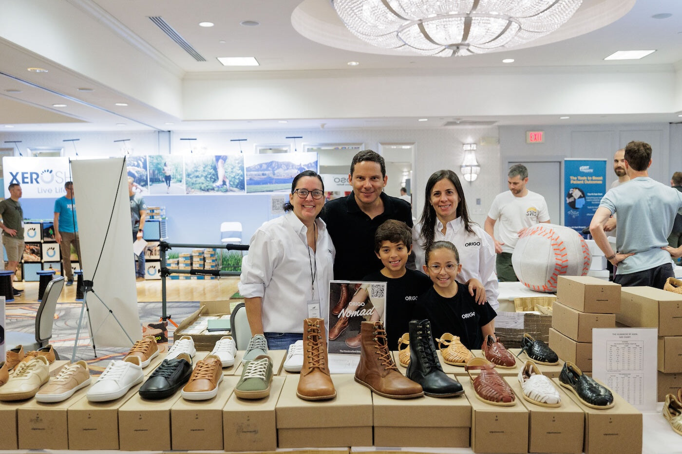 Exhibitors posing behind a table of barefoot shoes, photo by Barefoot Shoe Expo