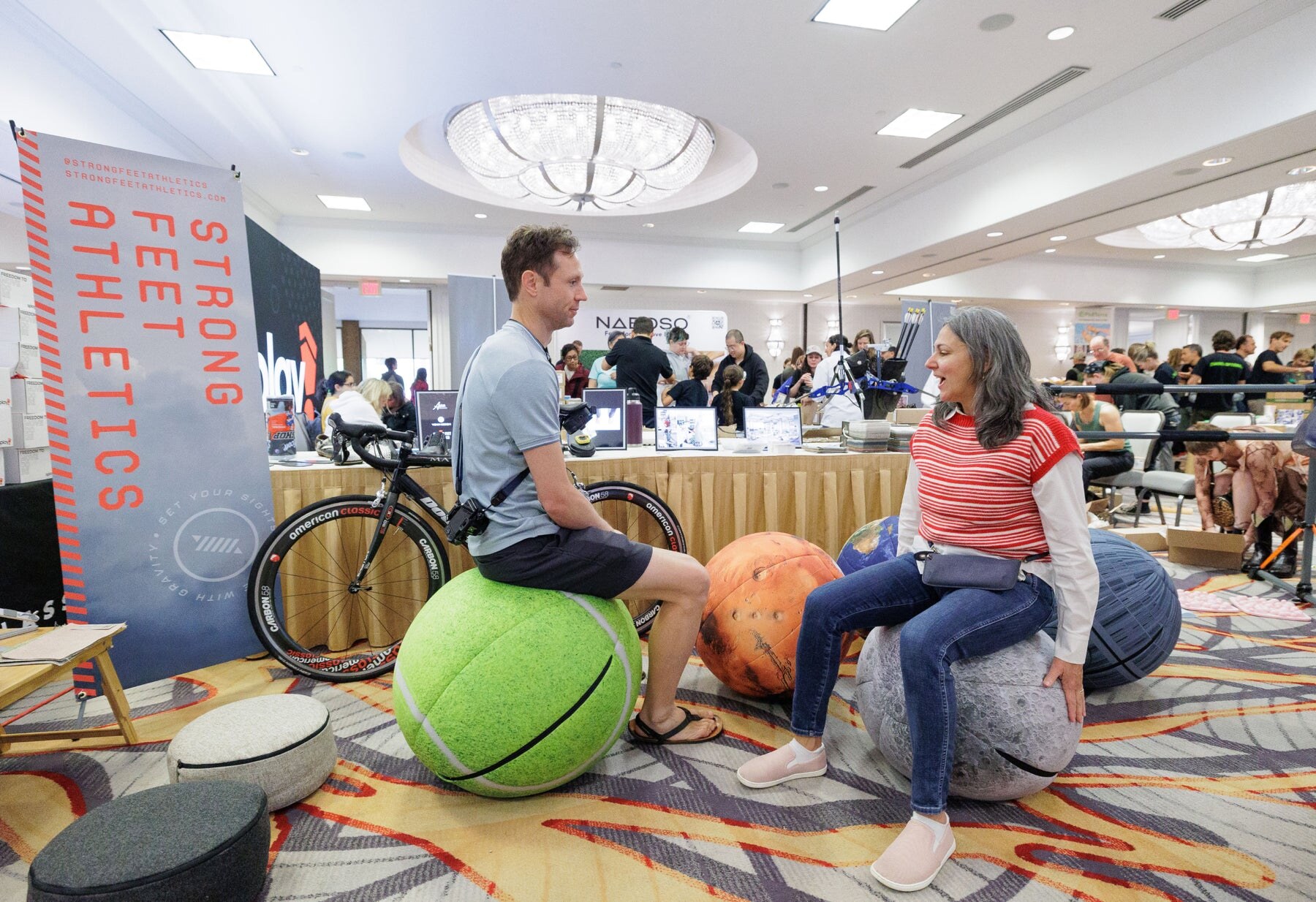 Two attendees talking while sitting on balance equipment, photo by Barefoot Shoe Expo