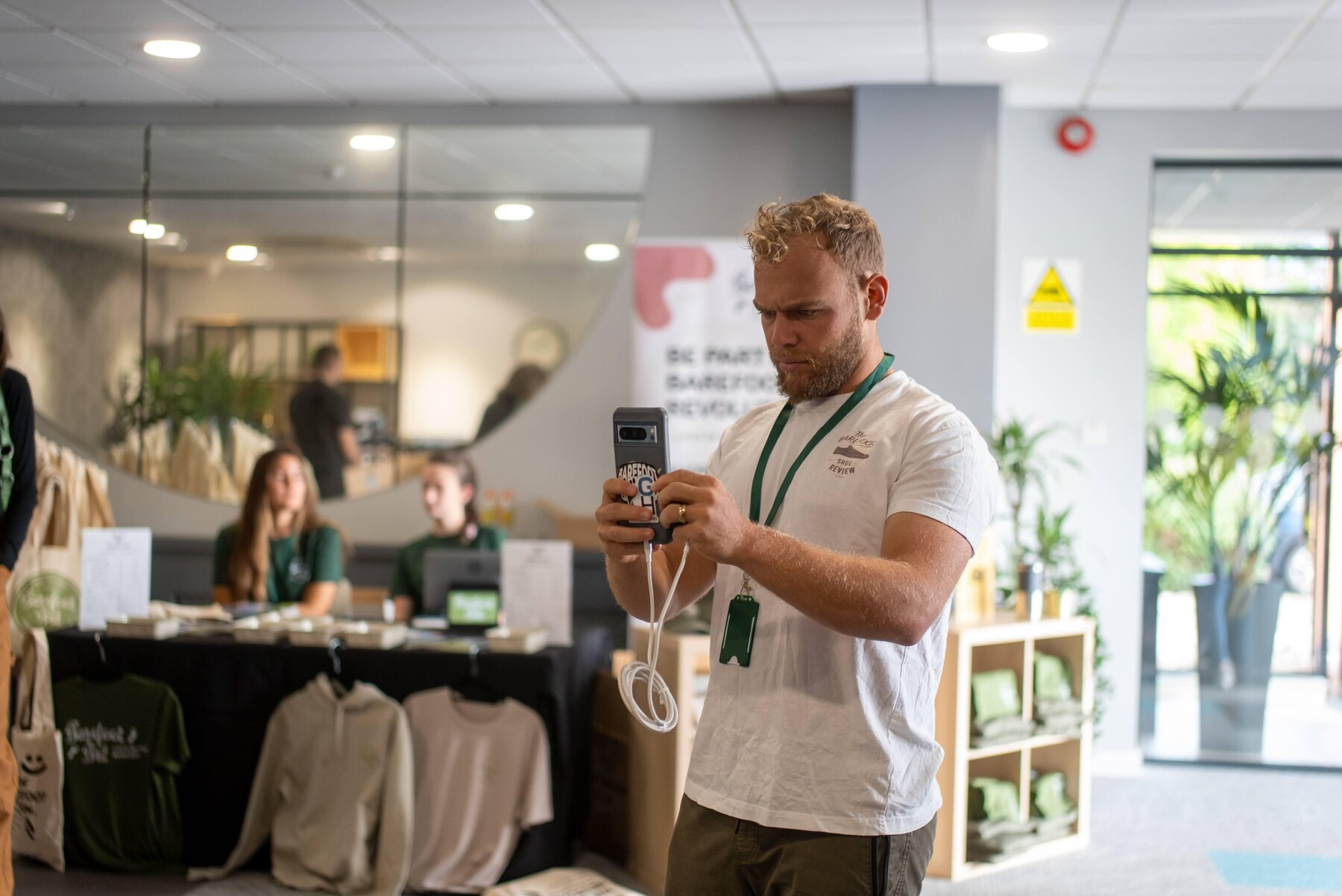 An attendee recording the event on his phone near the entrance, photo by Barefoot Brit Expo