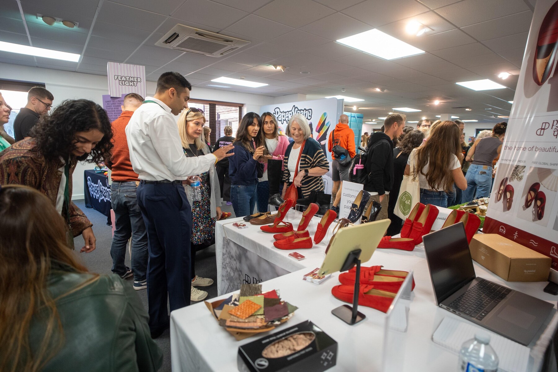 Visitors examining shoes and talking to exhibitors, photo by Barefoot Brit Expo