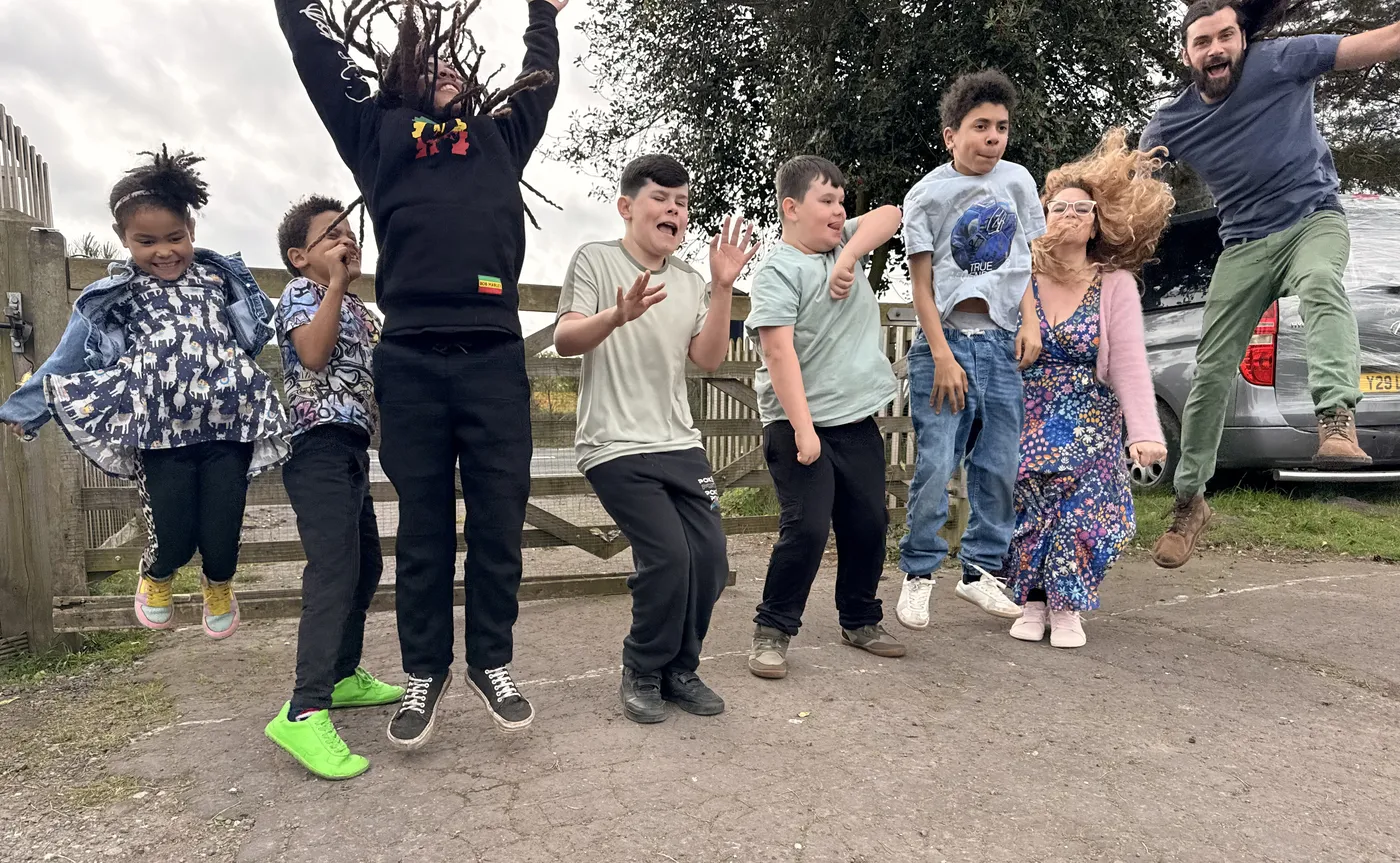 Dan, his wife and their six children all jumping in the air together outside